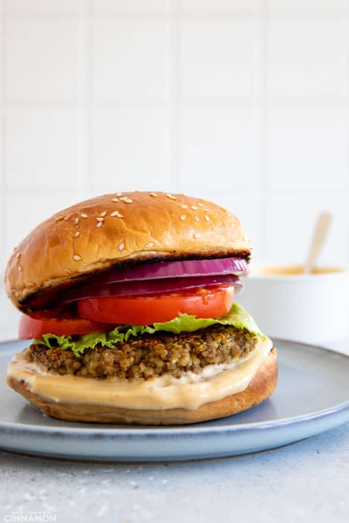 side view of a glutenfree mushroom quinoa burger with tomatoes, lettuce and homemade miso aioli