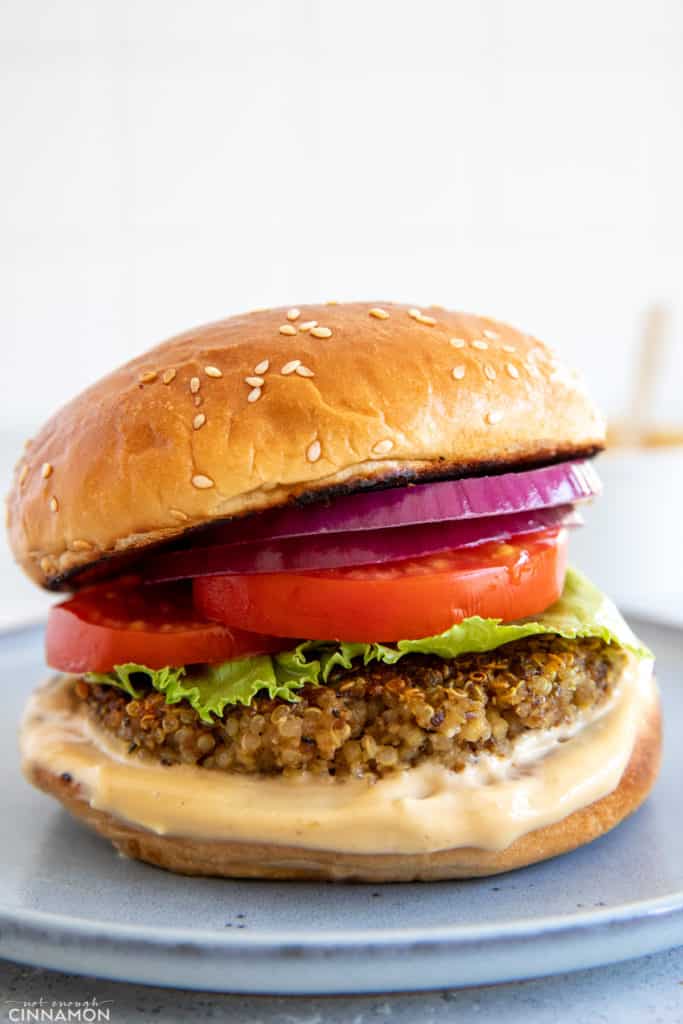 Shiitake Mushroom Quinoa Burger patty served in a burger bun with tomato onion and lettuce as well as a miso aioli